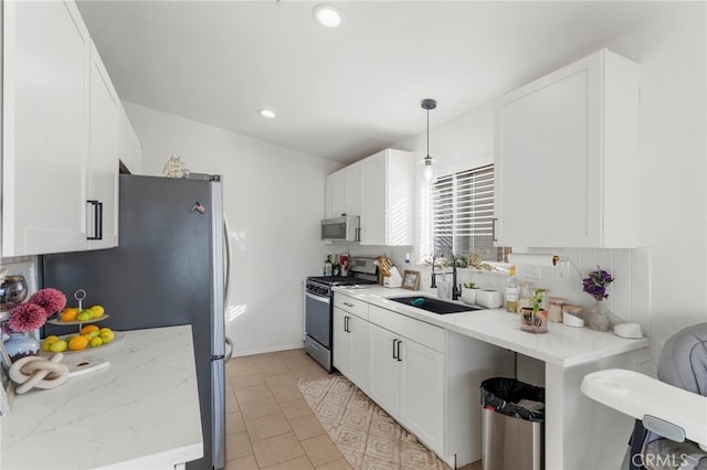 kitchen featuring stainless steel appliances, white cabinetry, and decorative light fixtures