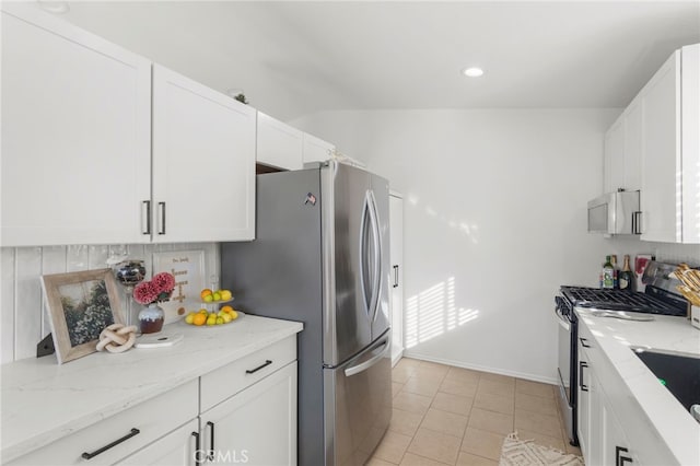 kitchen with light stone counters, white cabinets, appliances with stainless steel finishes, and light tile patterned floors