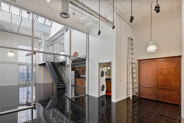 stairs featuring stacked washer / dryer, a wall of windows, a towering ceiling, and tile patterned flooring