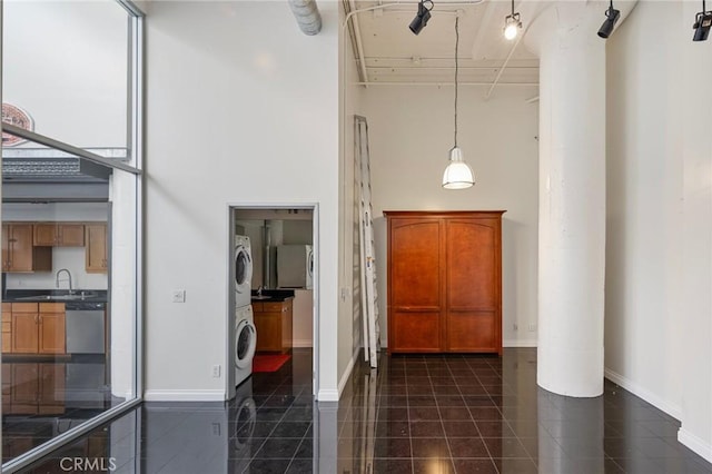 hallway featuring a high ceiling, stacked washer / drying machine, and sink