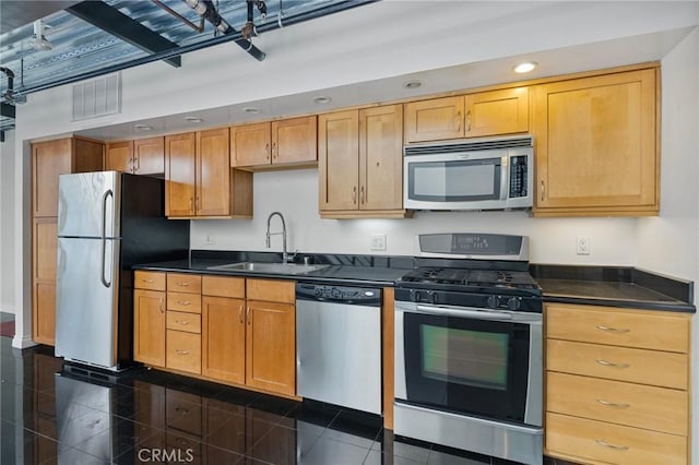 kitchen with stainless steel appliances, dark tile patterned flooring, and sink