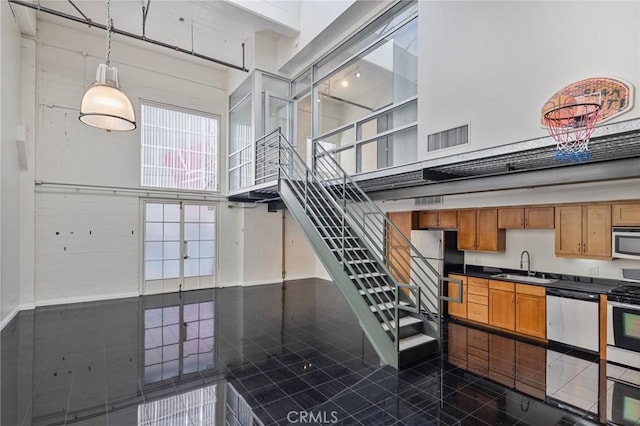 stairway featuring a towering ceiling and sink