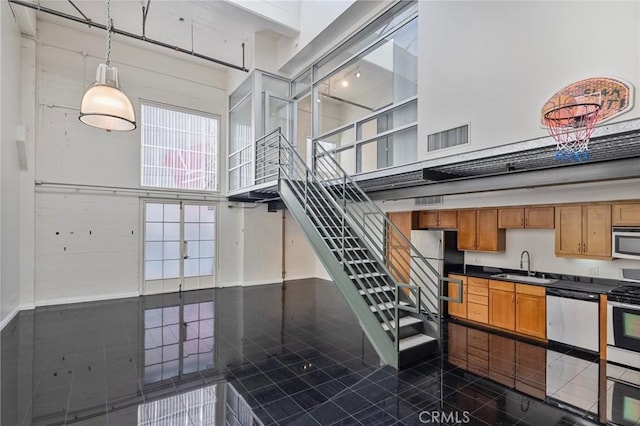 staircase featuring a high ceiling, tile patterned floors, and sink