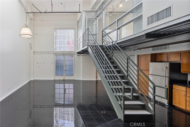 staircase featuring tile patterned floors and a high ceiling