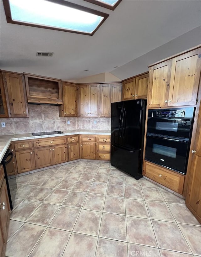 kitchen with black appliances, backsplash, light tile patterned flooring, and custom range hood