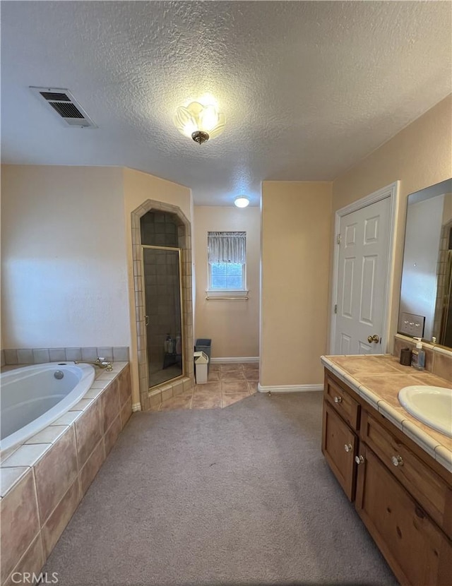 bathroom with a textured ceiling, vanity, and separate shower and tub