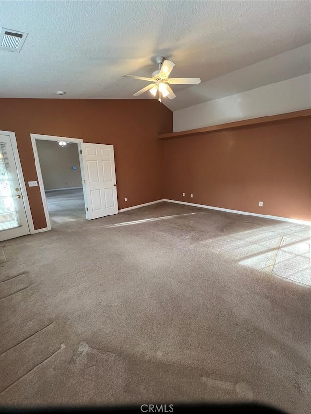 carpeted spare room featuring vaulted ceiling, ceiling fan, and a textured ceiling