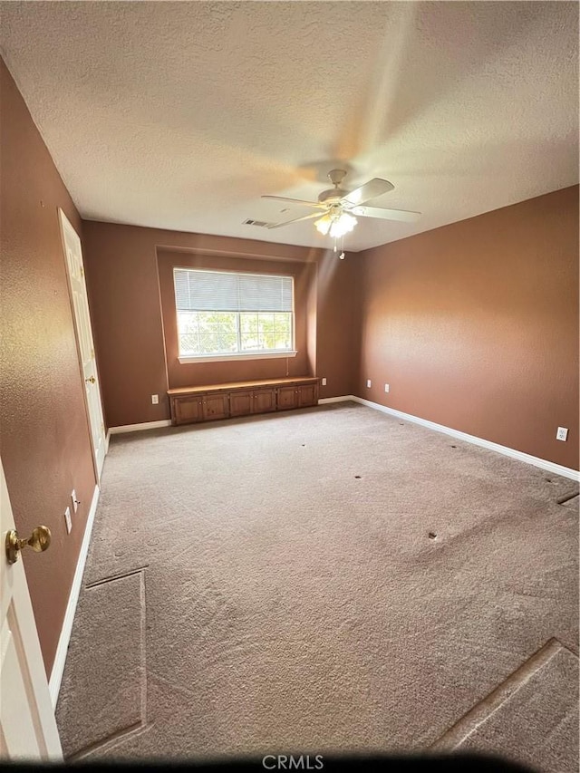 unfurnished room with a textured ceiling, ceiling fan, and carpet flooring