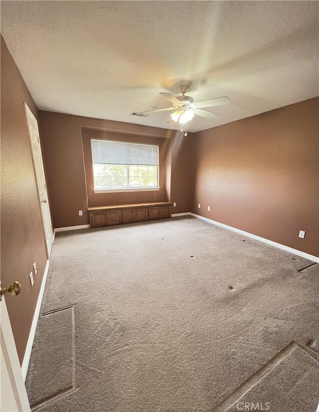 spare room featuring a textured ceiling, ceiling fan, and carpet floors