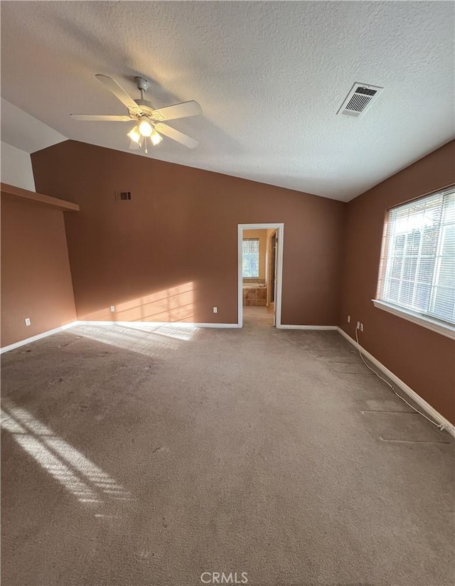 carpeted empty room with ceiling fan, a textured ceiling, a healthy amount of sunlight, and vaulted ceiling