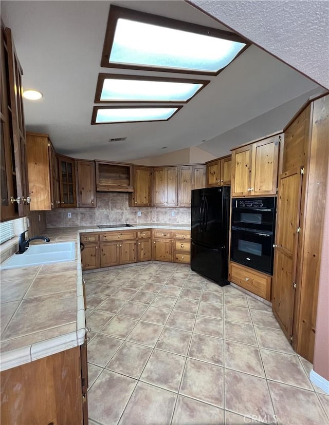 kitchen with black appliances, sink, backsplash, tile countertops, and light tile patterned floors