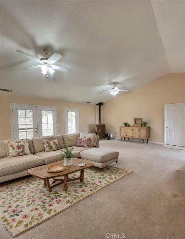 carpeted living room featuring vaulted ceiling, ceiling fan, and a wood stove