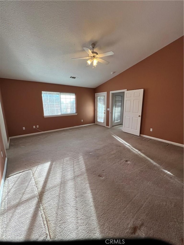 spare room with lofted ceiling, ceiling fan, carpet floors, and a textured ceiling