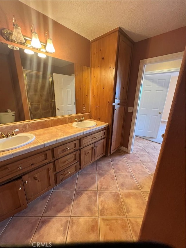 bathroom with a textured ceiling, toilet, vanity, and tile patterned flooring