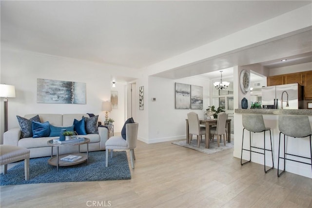 living room with ornamental molding, light hardwood / wood-style flooring, and a notable chandelier