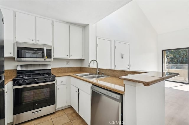18808 Mandan St Unit 312, Canyon Country, CA 91351 - kitchen featuring vaulted ceiling, a peninsula, white cabinetry, appliances with stainless steel finishes, and a sink