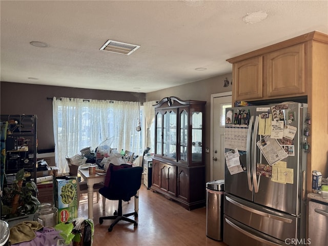 kitchen with a textured ceiling, dark hardwood / wood-style flooring, and stainless steel fridge