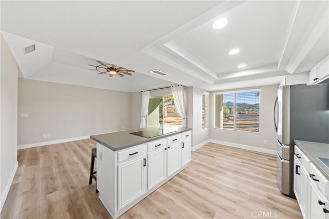 kitchen featuring light wood-style floors, visible vents, a tray ceiling, and freestanding refrigerator