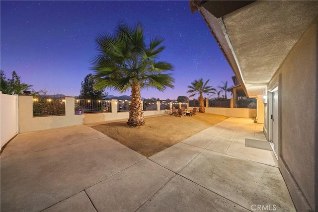 yard at dusk featuring a fenced front yard and a patio