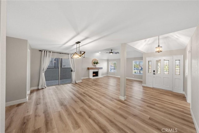 unfurnished living room with a warm lit fireplace, baseboards, and light wood-style floors