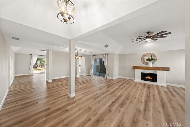 unfurnished living room with light wood finished floors, a fireplace, baseboards, and ceiling fan with notable chandelier