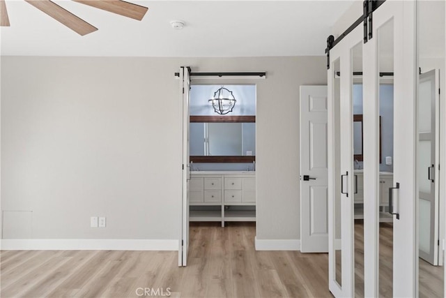 interior space with baseboards, a barn door, and light wood-style floors