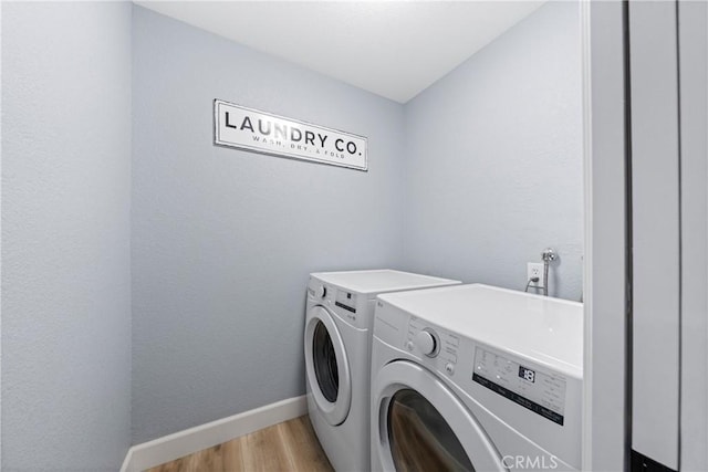 laundry area with laundry area, washing machine and dryer, baseboards, and light wood-style flooring