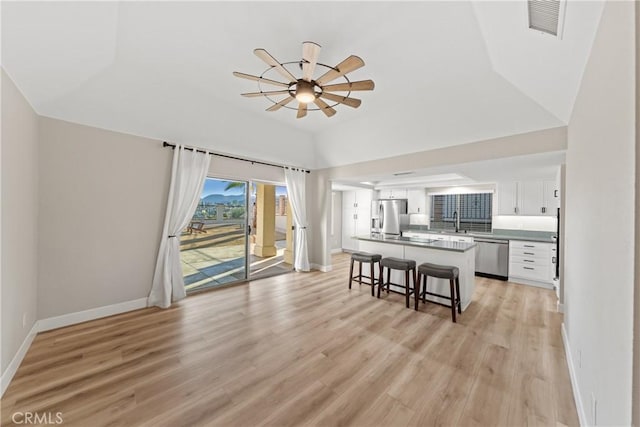 living room with ceiling fan, light wood finished floors, visible vents, and baseboards