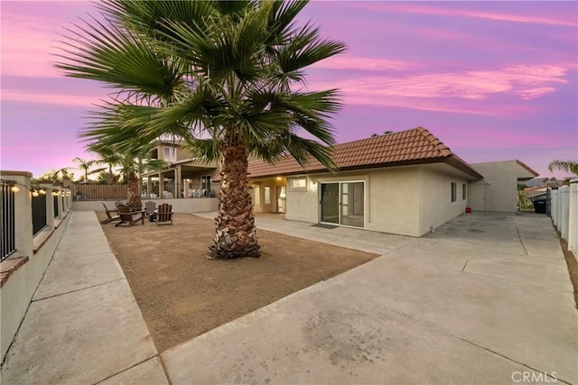 rear view of house featuring a patio area, fence, a tile roof, and stucco siding