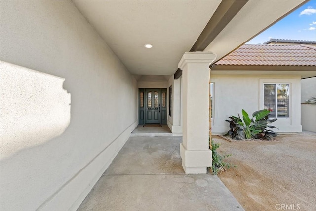 entrance to property with a tile roof and stucco siding