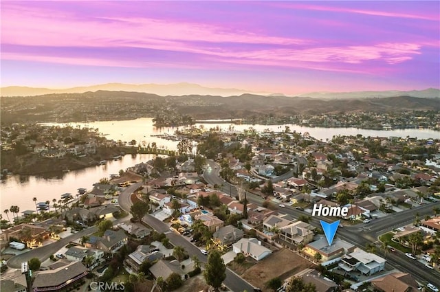 aerial view at dusk featuring a water and mountain view