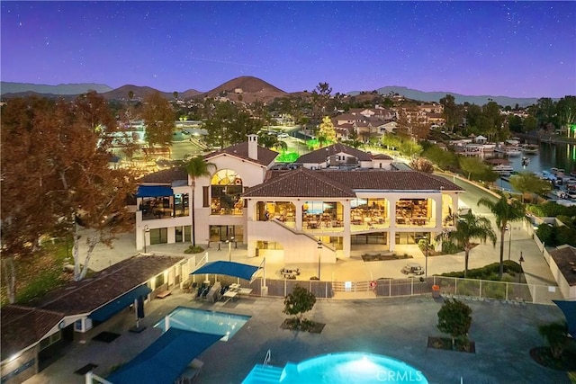 rear view of property with a balcony, a mountain view, a fenced in pool, and a patio