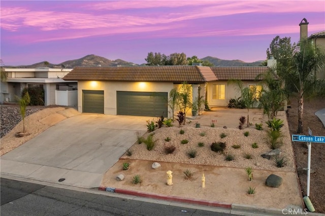 ranch-style house featuring driveway, an attached garage, a mountain view, and stucco siding