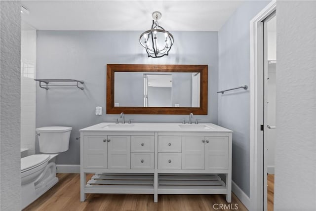 full bath featuring double vanity, wood finished floors, a sink, and toilet