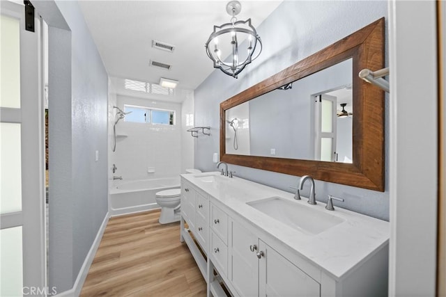 bathroom with double vanity, visible vents, toilet, wood finished floors, and a sink