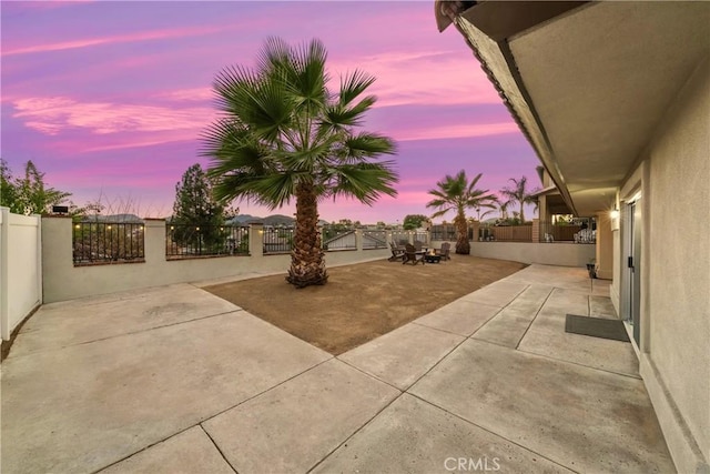 patio terrace at dusk featuring a fenced backyard