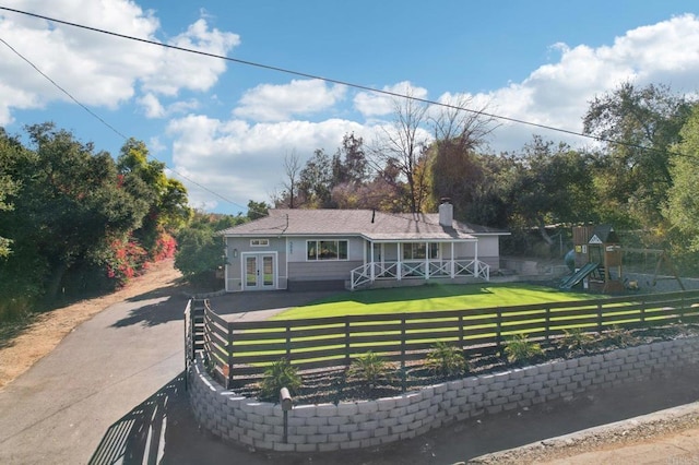 view of front of property featuring a front lawn, french doors, and a playground