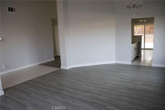 spare room with dark hardwood / wood-style flooring and a chandelier