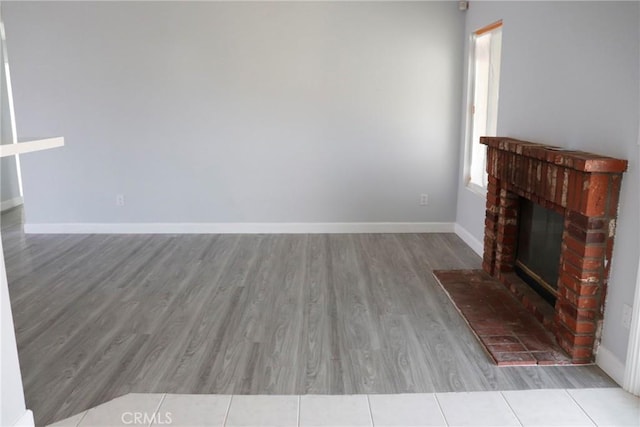 unfurnished living room with a brick fireplace and light hardwood / wood-style flooring