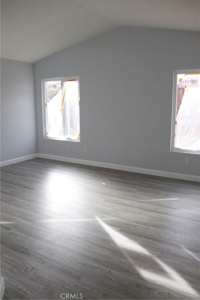 empty room with dark wood-type flooring and vaulted ceiling