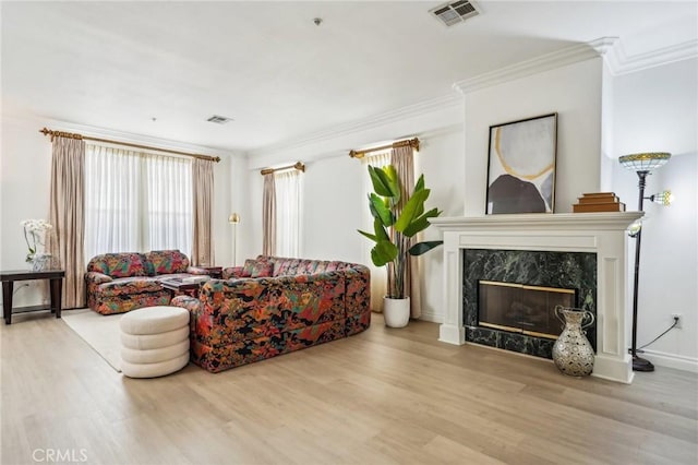 living room featuring light wood-type flooring, ornamental molding, and a fireplace