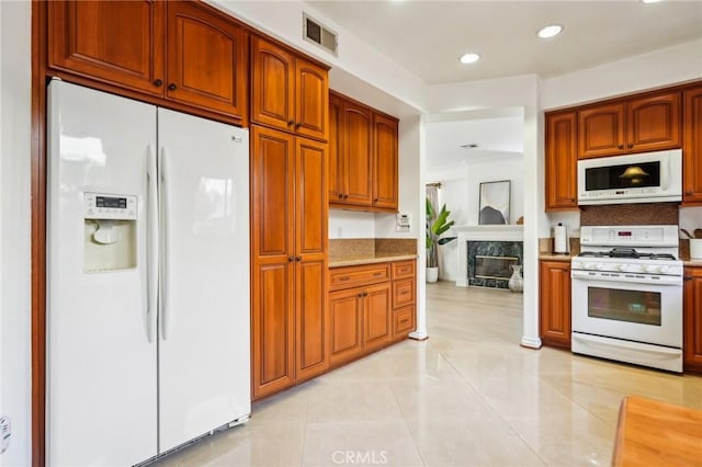 kitchen with light tile patterned floors, a high end fireplace, and white appliances