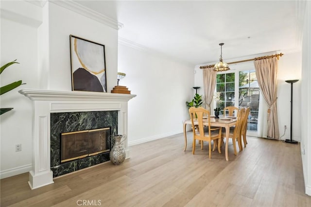 dining area featuring light hardwood / wood-style floors, an inviting chandelier, ornamental molding, and a fireplace