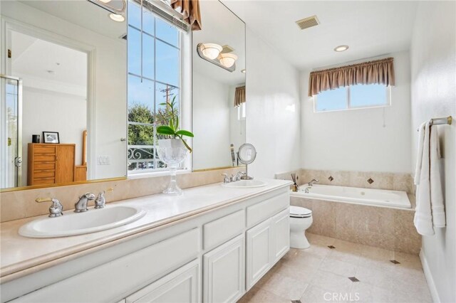 bathroom featuring toilet, vanity, tile patterned floors, and tiled tub