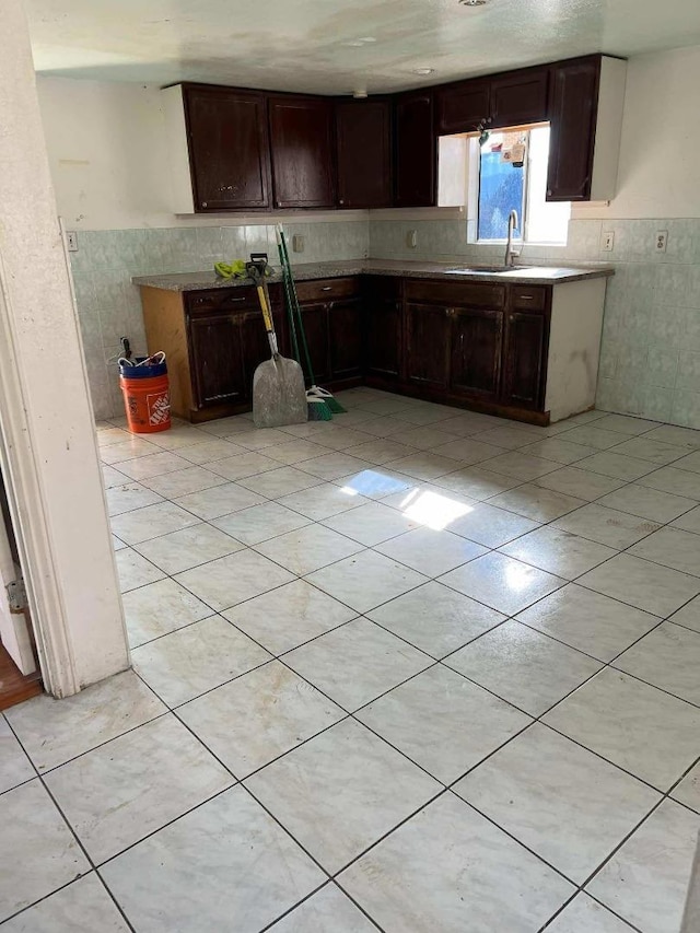 kitchen featuring light tile patterned flooring, dark brown cabinetry, and sink