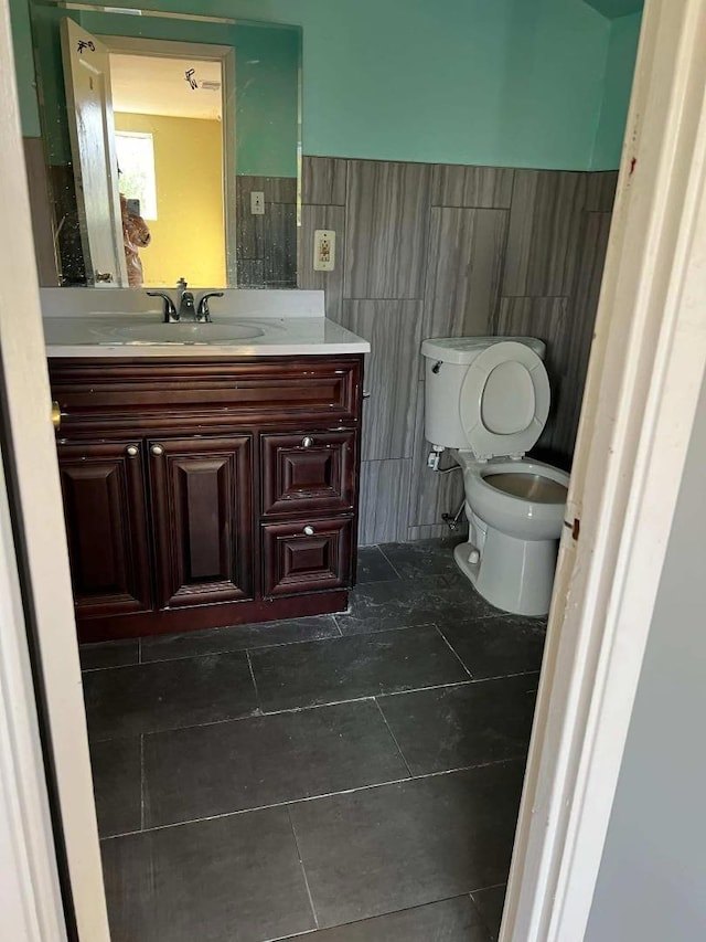 bathroom with toilet, vanity, and tile walls