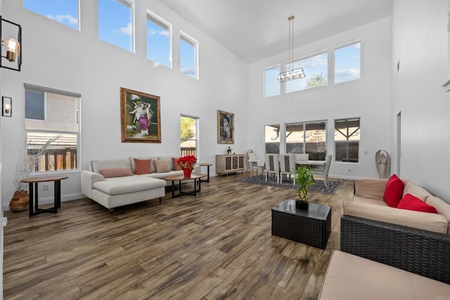 living room with a wealth of natural light, a high ceiling, a chandelier, and hardwood / wood-style floors