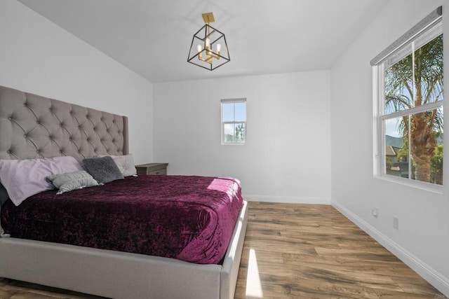 bedroom featuring a notable chandelier, multiple windows, and hardwood / wood-style flooring