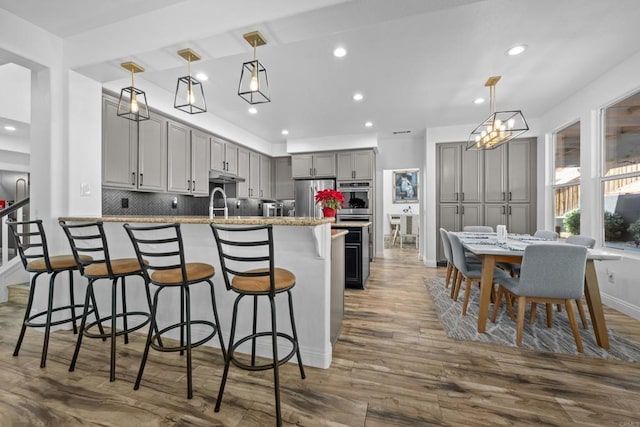 kitchen featuring backsplash, gray cabinets, hanging light fixtures, dark wood-type flooring, and stainless steel appliances