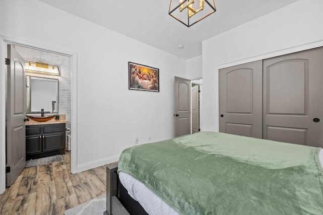 bedroom featuring ensuite bathroom, a closet, an inviting chandelier, and light hardwood / wood-style flooring